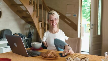 Yung beautiful woman born without arms answers the phone using her legs while having breakfast working on the laptop at home