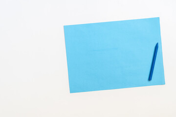 A sheet of blue paper next to a blue crayon