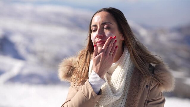 Positive Middle age female applying sunscreen on her face in snow landscape