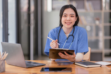 Portrait of Young Asian smiling female nurse working on laptop in private clinic, Positive emotional and good moment.Health Care Concept.