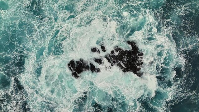 Ocean waves with white foam breaking on the rocks. Aerial top down shot of stormy ocean surf. Sea or ocean wave splashing