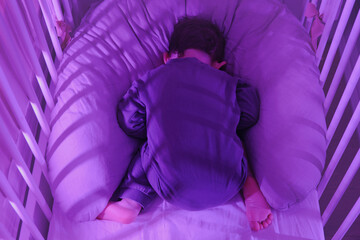 Toddler baby sleeps face down on his stomach while lying in a crib. Funny child boy sleeps upside...