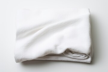 A white towel that is folded and separated from its background by being placed on a white surface