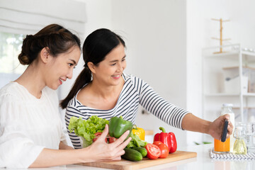 Asian woman girlfriends smiles, holds bell pepper and takes selfies in kitchen