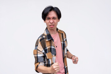 A vindicated young asian man celebrating, pumping his fist. Feeling amped and stoked. Isolated on a white background.