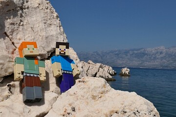 Obraz premium LEGO Minecraft main characters Alex and Steve standing on rocks sunlit rocky beach of Razanovac near Razanac town, northern Dalmatia. 