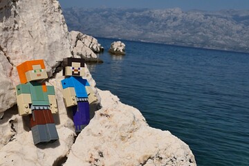 Obraz premium LEGO Minecraft main characters Alex and Steve sunbathing on rocks sunlit rocky beach of Razanovac near Razanac town, northern Dalmatia. 