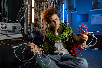 Confused IT networking engineer looking with disbelief on ethernet cables