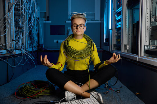 Calm female IT technician meditating in server room