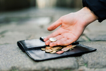 Female hands coins with wallet on paving stones street background