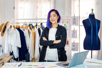 Portrait of Asian fashionable freelance dressmaker in her artistic workshop studio for fashion design and clothing business industry