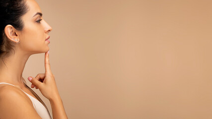 Side view of millennial woman wearing top touching her chin