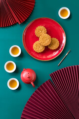 Flat lay mid autumn festival decorative objects, food and tea on coloured background still life.