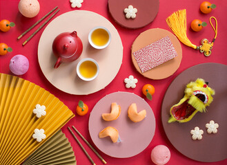 Flat lay Chinese new year decorative objects, food and tea on coloured background still life.
