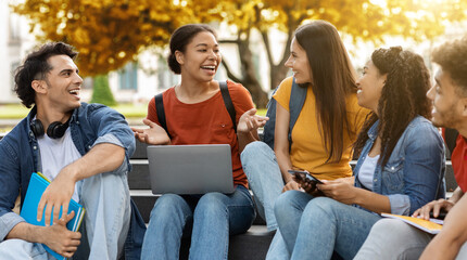 Diverse multiethnic students sitting on stairs outdoors in university campus