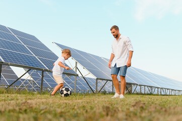 Father and son playing football in garden of solar paneled