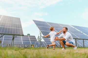 Smiling father and his little child on background of solar panels. Young father enjoy spending time with his son. Happy family of two on background of solar panels.
