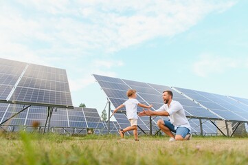 Smiling father and his little child on background of solar panels. Young father enjoy spending time...