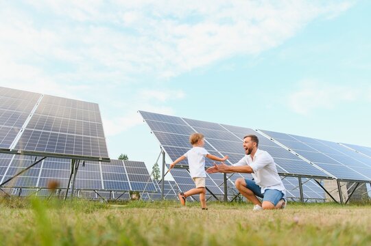 Smiling father and his little child on background of solar panels. Young father enjoy spending time with his son. Happy family of two on background of solar panels.