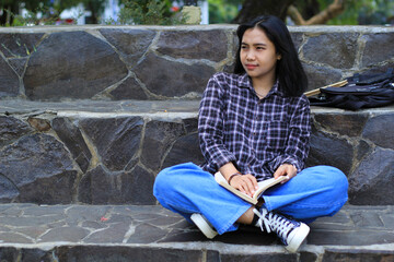 excited asian beautiful young woman college student smiling with happy face reading a book outdoor, campus university concept