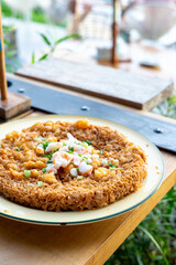 A Thai style crispy omelette with shrimps is a simple and delicious dish that can be enjoyed for breakfast or as a rice topper. A Thai style crispy omelette is in a plate on the table.