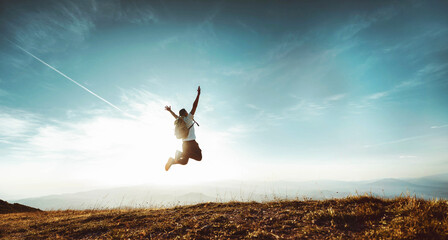 Happy man with arms up jumping on the top of the mountain - Successful hiker celebrating success on...