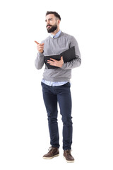 Confident stylish bearded businessman holding notebook pointing and looking away. Full body length portrait isolated on transparent background.