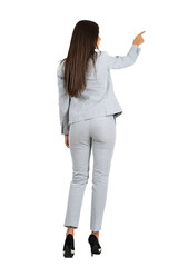 Rear view of young business woman in suit pointing to the right. Full body isolated on transparent background.