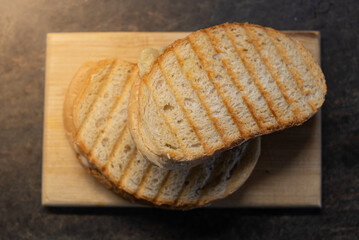 Tasty home made toasted white bread with cheese on wooden plate.