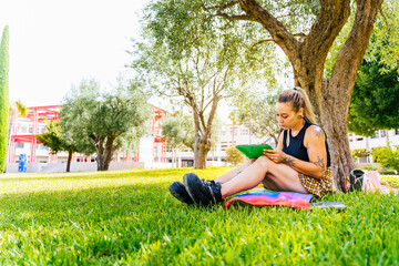 Modern college student with tattoos sitting on the university lawn over the LGBT flag