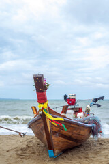 A Thai long-tail fishing boat on the beach looks like a colorful and exotic sight, is a traditional wooden boat with a long propeller shaft that extends from the back.