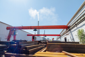 Worker transporting stack of metal pipes with gantry crane