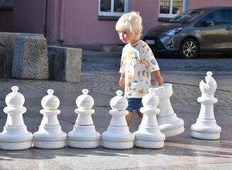 Little cute toddler boy playing outdoor chess