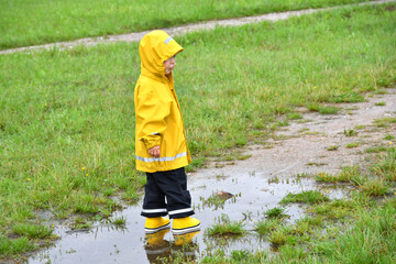 Little boy standing in a muddy puddle on a rainy fall day