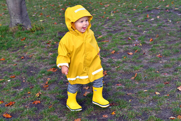 Happy emotional kid enjoing rainy weather in the park