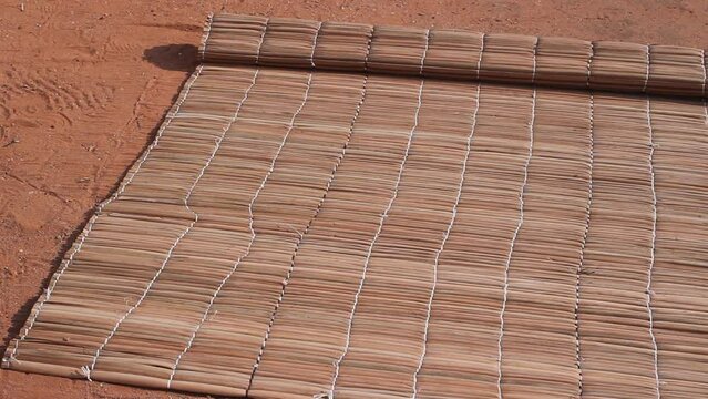 Laying a traditional straw mat on the sand