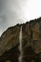 Close Up View of a Waterfall in the Swiss Alps with mountains in the background in Switzerland in Summer