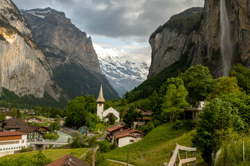 Fototapeta na wymiar Buildings and a Church Sitting Along the Hills high up in Lauterbrunnen in the Swiss Alps with mountains in the background in Switzerland in Summer