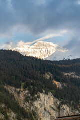 Fototapeta premium Mountain Peaking Through the Clouds at Sunset in the Swiss Alps in Switzerland in the Summer 