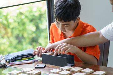 Asian father and son playing wood blocks game Carefree kid playing wood blocks game building constructor from blocks with father at home