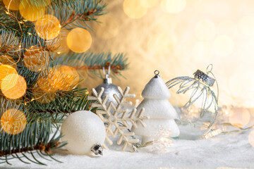 Fototapeta na wymiar Christmas decorations on a snowy table with fir branches and glowing garlands. Copy space