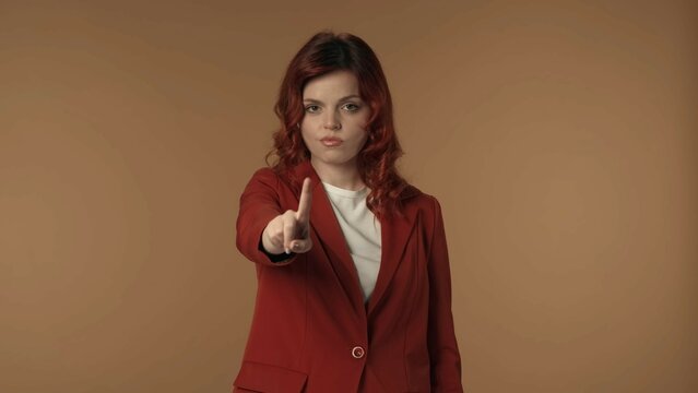 Medium isolated shot of a young woman pointing at the camera and negatively wagging her finger to show her disagreement, complaint about something.