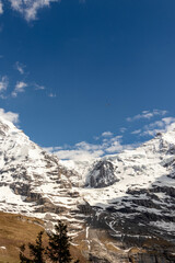 Obraz premium Close Up View of Snow Covered Mountain with Helicopter Flying By in the Swiss Alps in the Summer with Clouds in the Background in Switzerland