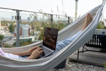 young woman freelancer working in hammock on terrace