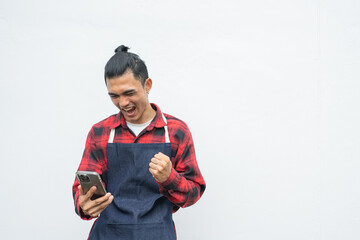 Asian young man Wearing a red and black plaid shirt, wearing a denim apron. happy with the deal