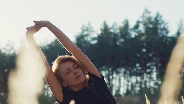 Athletic caucasian girl stretching in a wheat field after work out, athlete sport recreation post-workout recovery