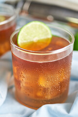  long island iced tea cocktail with strong drinks, cola, lime and ice in glass, cold longdrink or lemonade