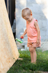 A little blond boy paints the wall with a roller.A kid in a T-shirt, shorts in the image of a...