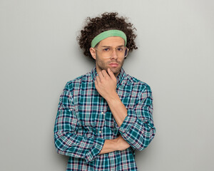Fototapeta na wymiar sexy curly hair guy with sport headband and glasses touching chin