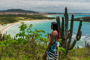 Woman enjoying the beautiful view of Praia das Conchas, near the city of Cabo Frio, with the blue sea around, undergrowth and mountains in the background - 137